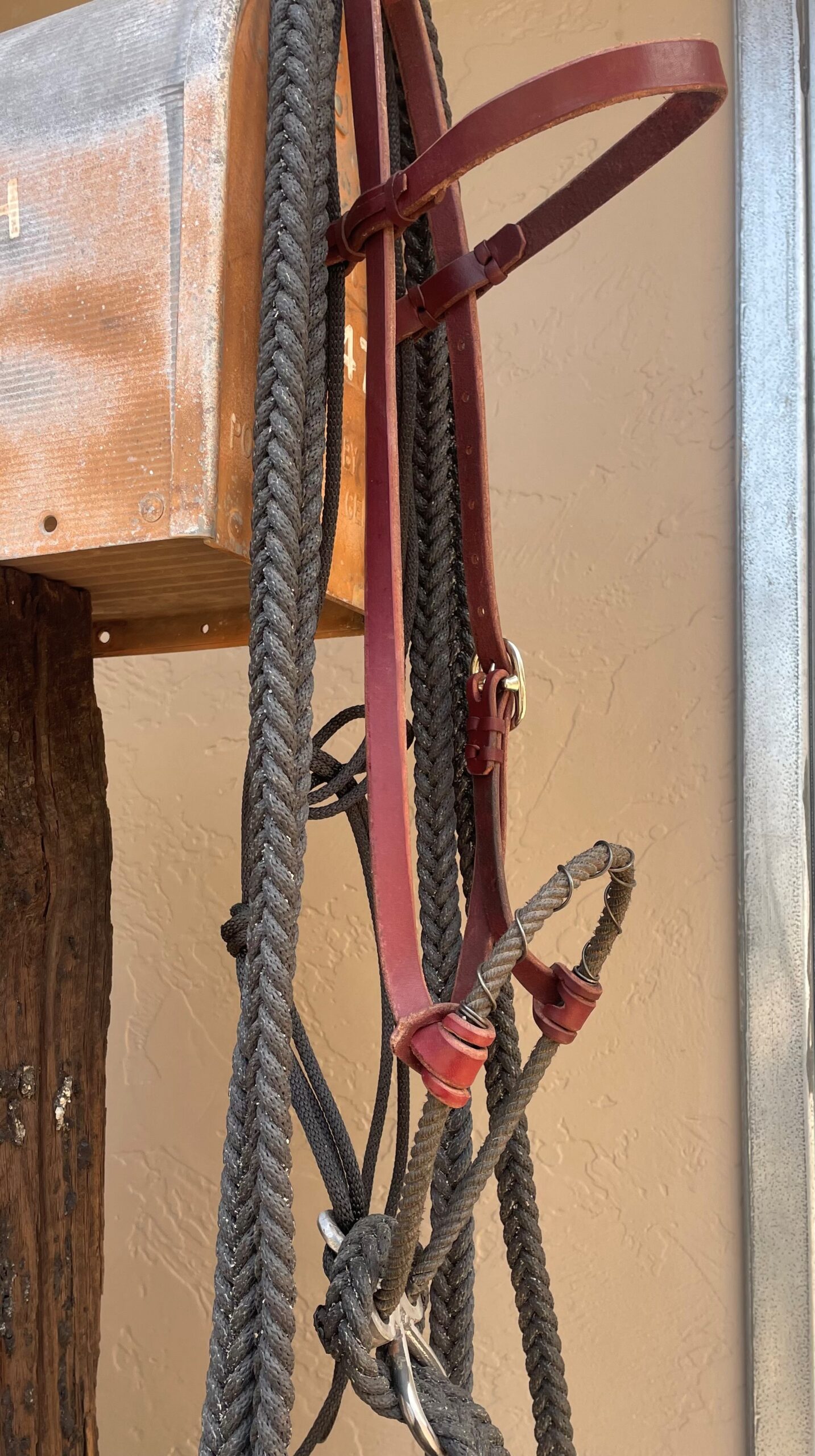 photo of leather headstall with lariat noseband, wrapped in wire. hanging on old mail box.